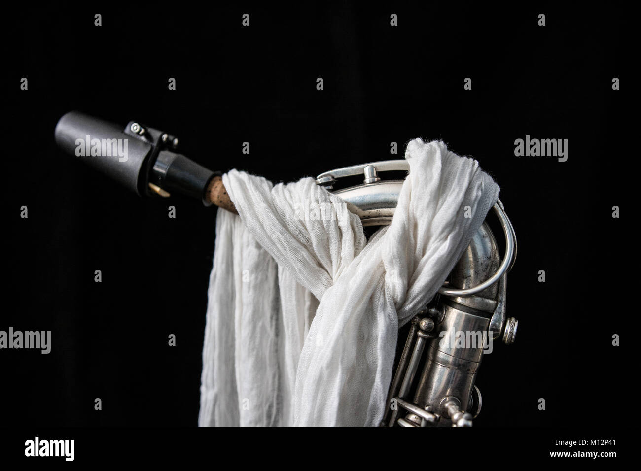 Nahaufnahme von einem Saxophon dekoriert mit einem weißen Tuch in Schwarz isoliert Stockfoto