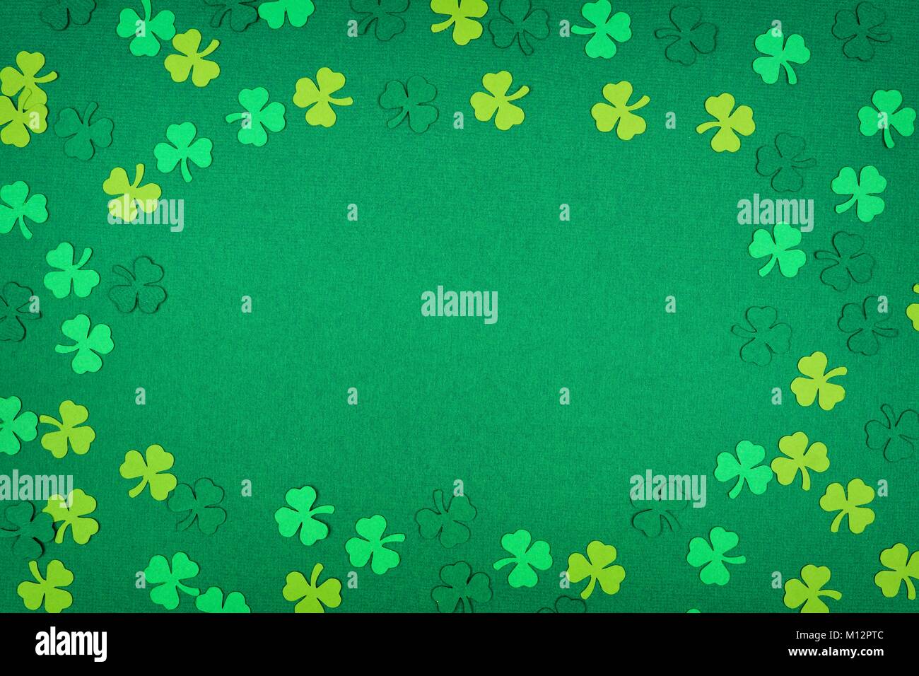 St Patricks Day frame Papier Shamrocks auf eine grüne strukturierten Hintergrund Stockfoto