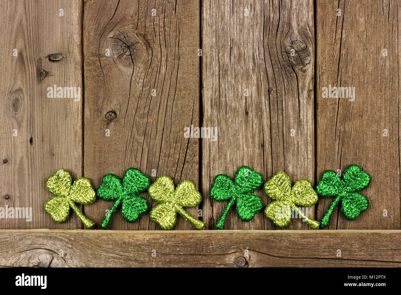 Reihe von St Patricks Day shamrocks gegen eine alte Holz- Hintergrund. Untere Grenze zu kopieren. Stockfoto