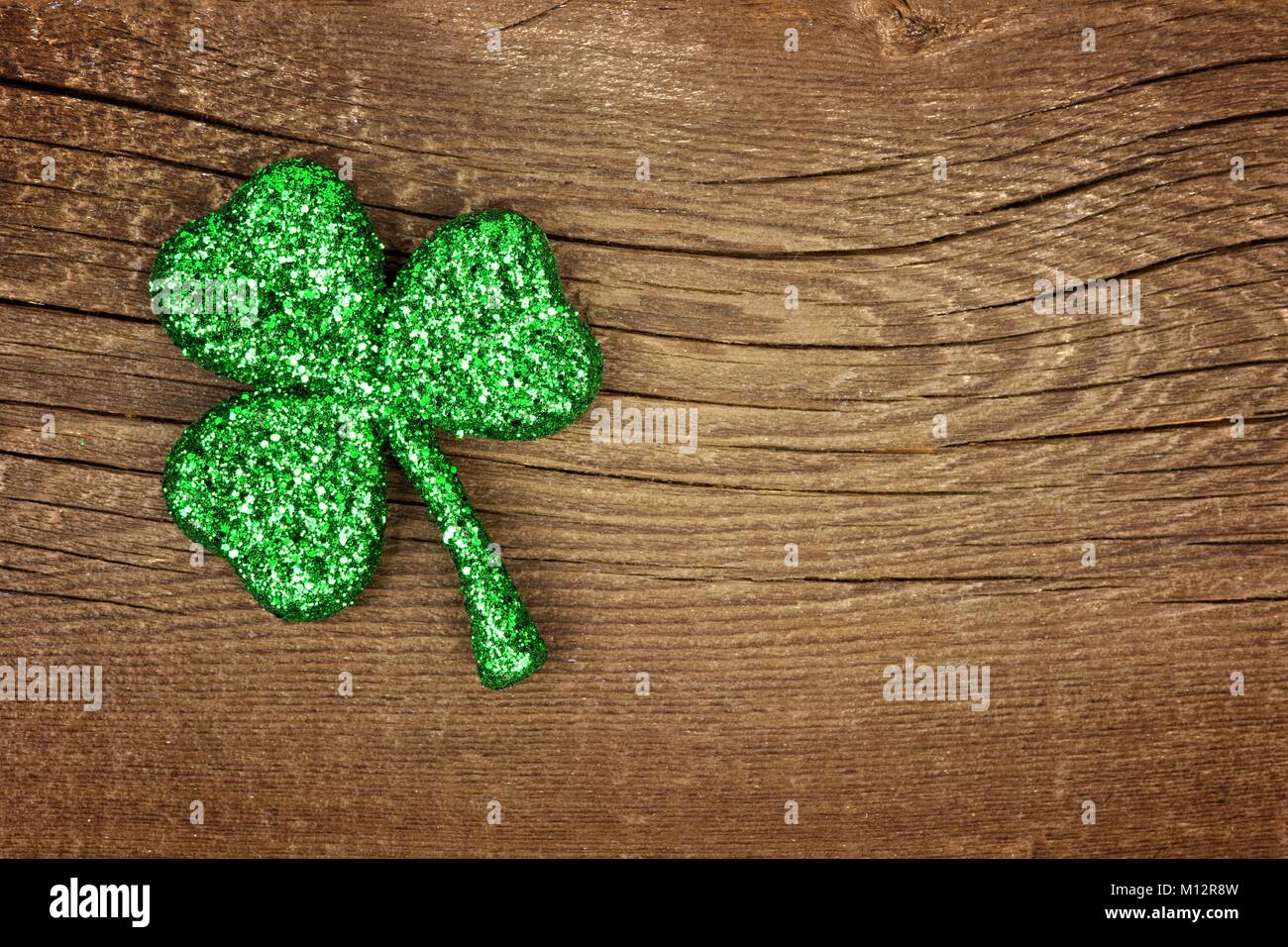 Einzelne St Patricks Day glittery Shamrock über ein altes rustikales Holz Hintergrund Stockfoto