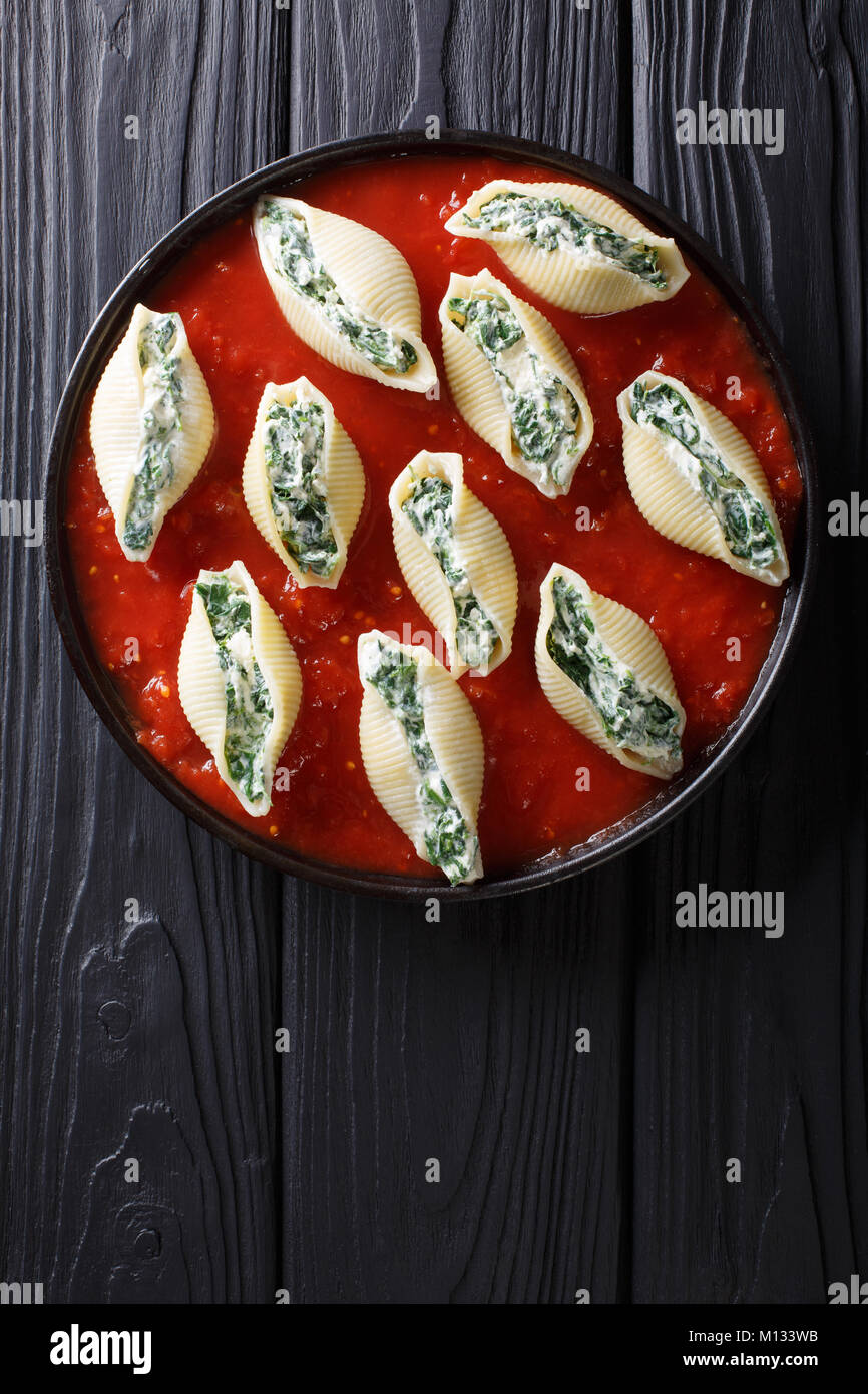 Shell Pasta mit Spinat und Frischkäse mit Tomatensauce closeup auf einem Teller. Vertikal oben Ansicht von oben Stockfoto