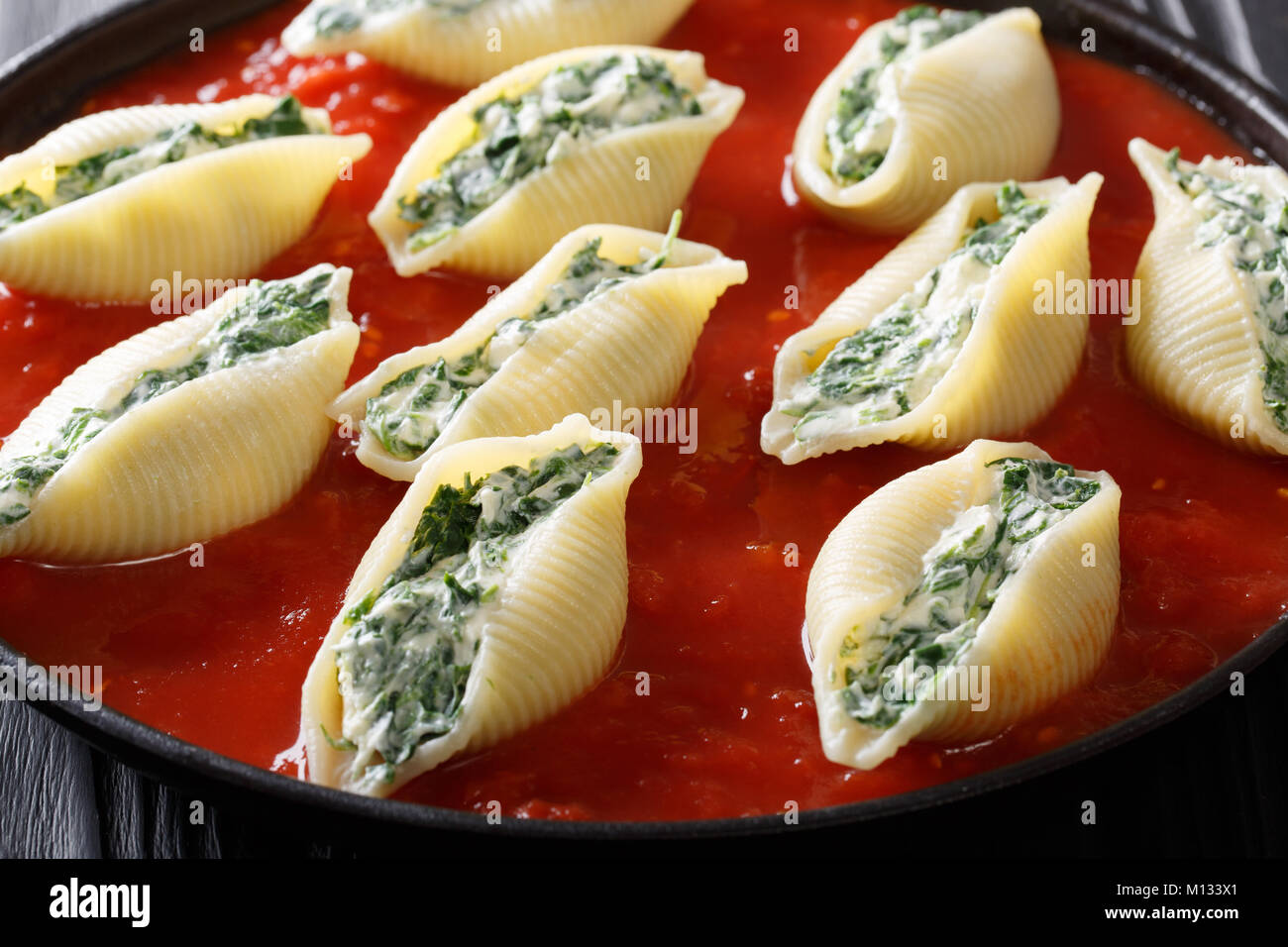 Italienische shell Pasta gefüllt mit Spinat und Ricotta mit Tomatensauce Makro auf einem Teller. Horizontale Stockfoto