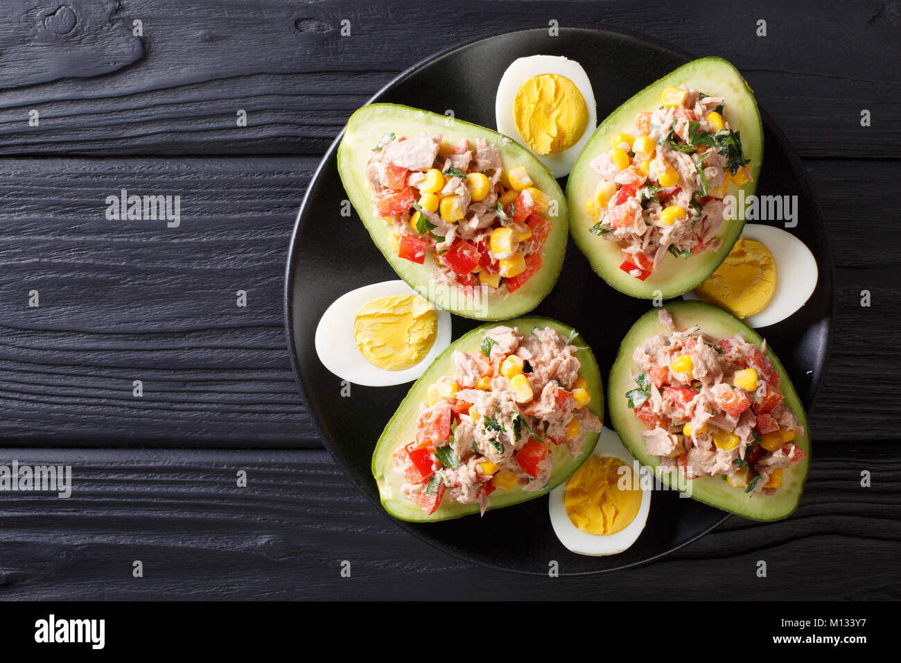 Leckerer snack von Avocado gefüllt mit Thunfisch salat Closeup auf einem Teller. horizontal oben Ansicht von oben Stockfoto