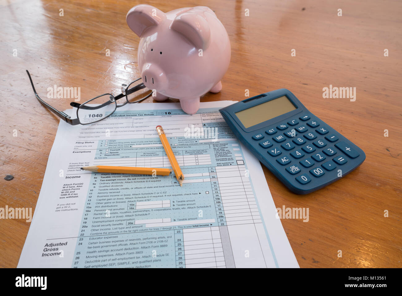 IRS Tax Form mit Sparschwein, Taschenrechner, Bleistift und Gläser Stockfoto