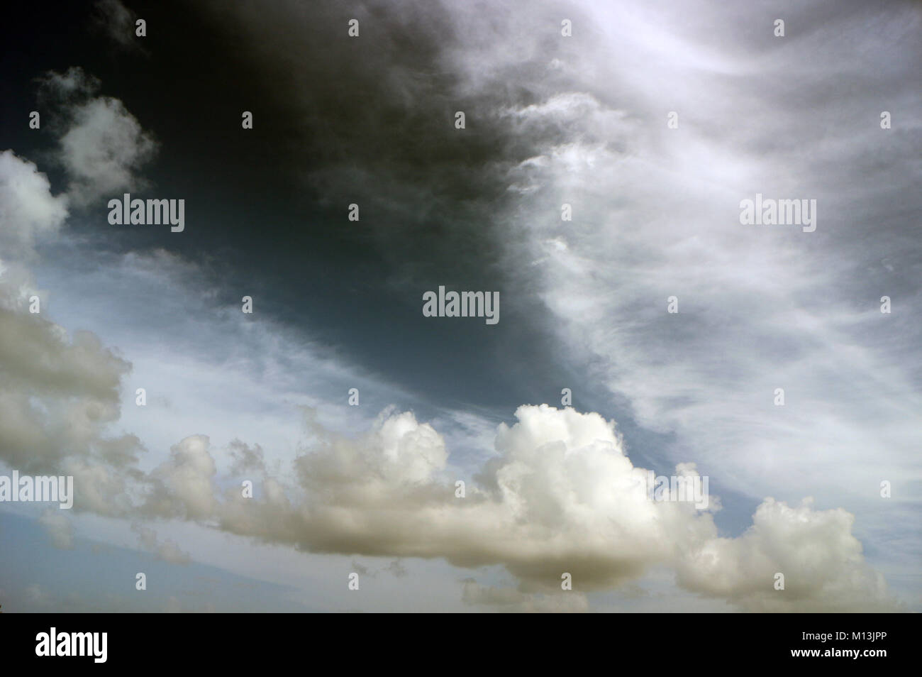 Schwere weiße Wolkenschichten in einem grauen Himmel mit weißen Streifen, Engelsflügel, Drachen, Seepferd oder Geistererscheinungen. Stockfoto