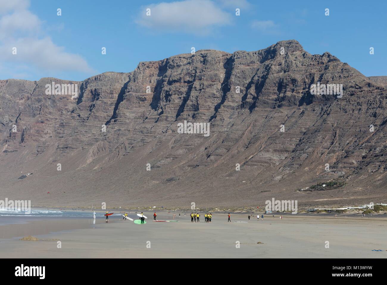 Spanien, Kanarische Inseln, Lanzarote, Caleta de Famara, am Famara Strand Surfer vor dem Risco de Famara Felsen Stockfoto