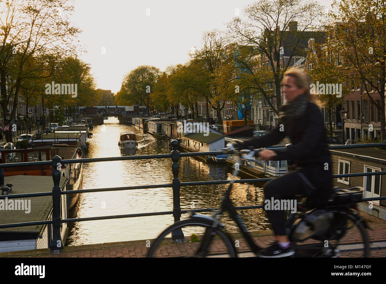 Frau Radfahren über Brücke auf oben sitzen und betteln, Fahrrad, Amsterdam, Niederlande Stockfoto