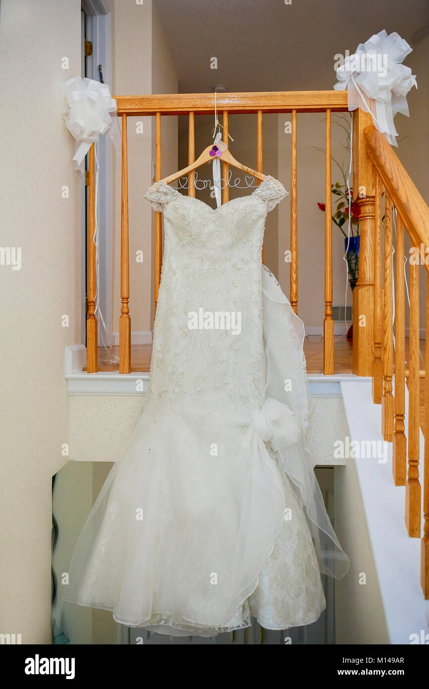 Das perfekte Hochzeitskleid mit einem vollen Rock auf einem Kleiderbügel in das Zimmer der Braut mit blauen Vorhängen Stockfoto