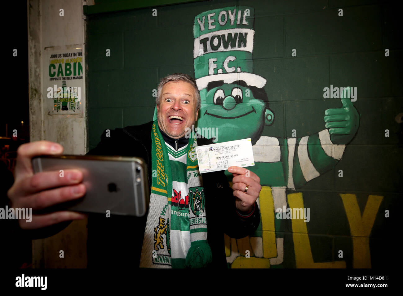 Ein yeovil Town fan posiert für ein selfie mit seinem Ticket und der Club Maskottchen Jolly Green Giant im Hintergrund, während Sie die Emirate FA Cup, vierte Runde bei Huish Park, Yeovil. Stockfoto