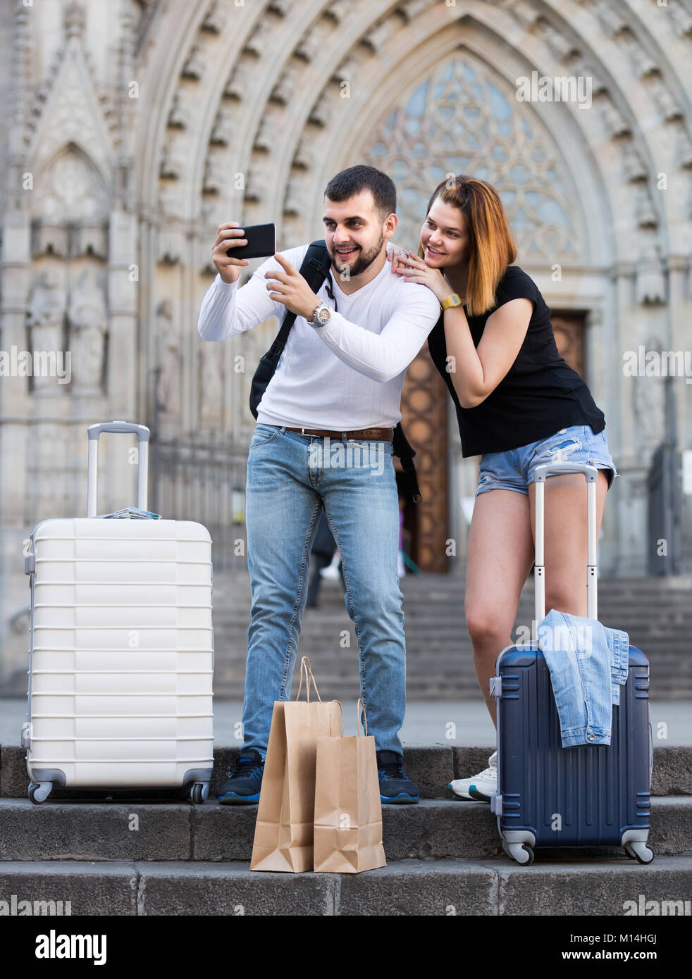 Lächelnd italienischen weiblichen und männlichen stehend mit Gepäck auf der Straße und Unter selfie Stockfoto