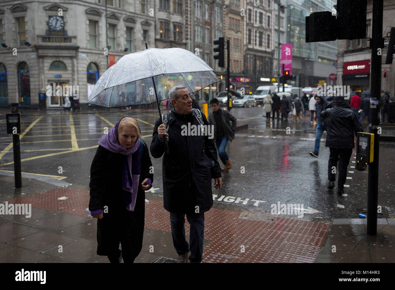 Sturm Georgina über Teile von Großbritannien und in Central London gefegt, mittags im Büro wurden durch sintflutartige Regenfälle und starke Winde gefangen, am 24. Januar 2018 in London, England. Fußgänger Zuflucht zu springen über tiefe Pfützen, an der Kreuzung von Oxford Street und der Kingsway in Holborn, die durch die Kanalisation überläuft. Stockfoto