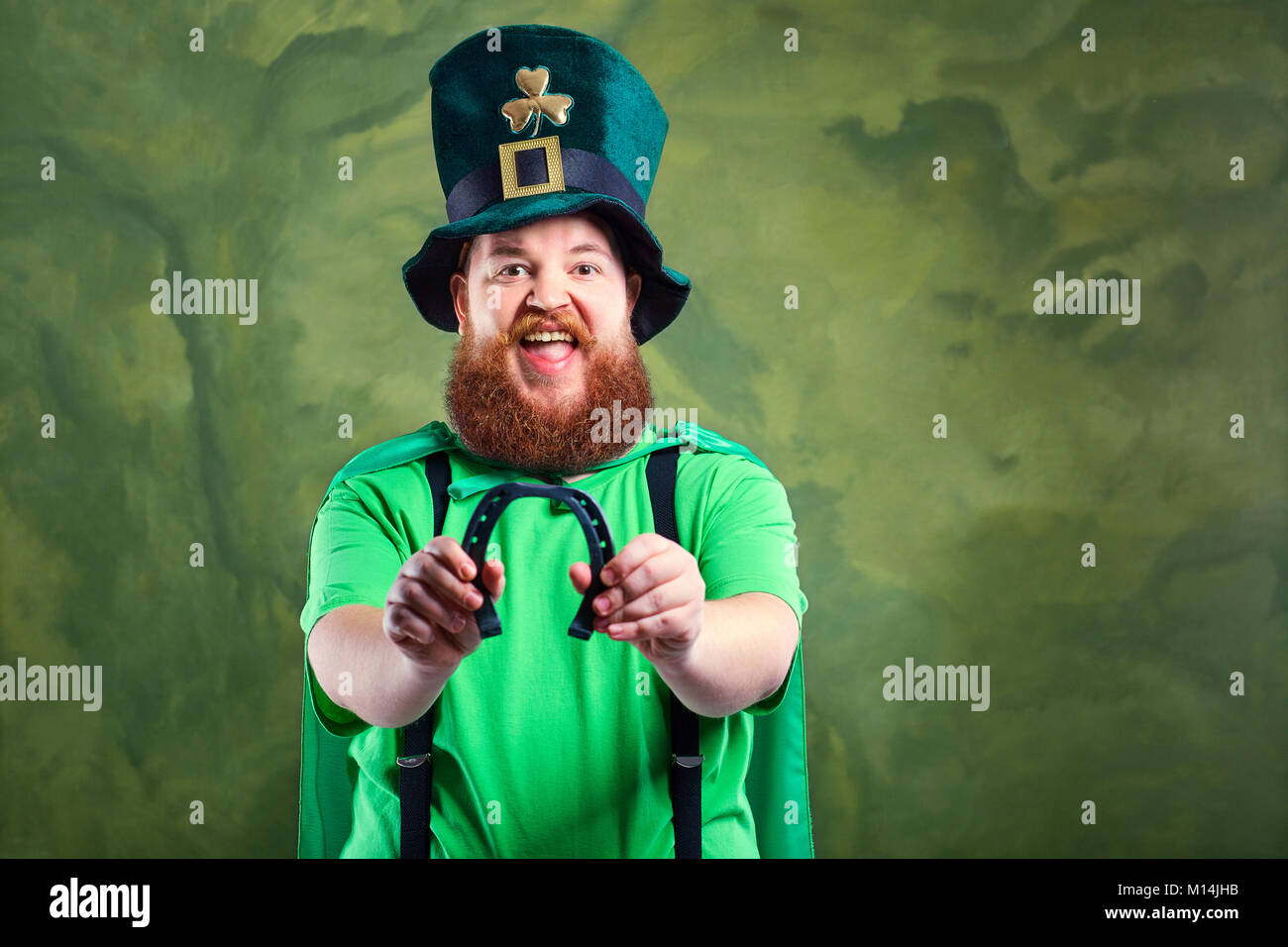 Ein dicker Mann mit Bart in der Klage von St. Patrick lächelt ein Pferd Stockfoto