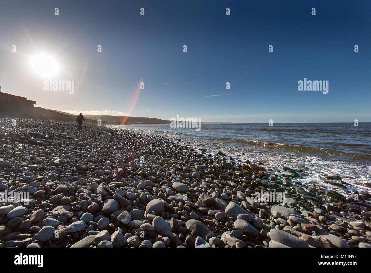 Die Wales Ceredigion Coast Path. Eine weibliche Wanderer auf einem felsigen Strand auf Wales Coast Path Route, zwischen den Dörfern Llanon und Aberarth. Stockfoto