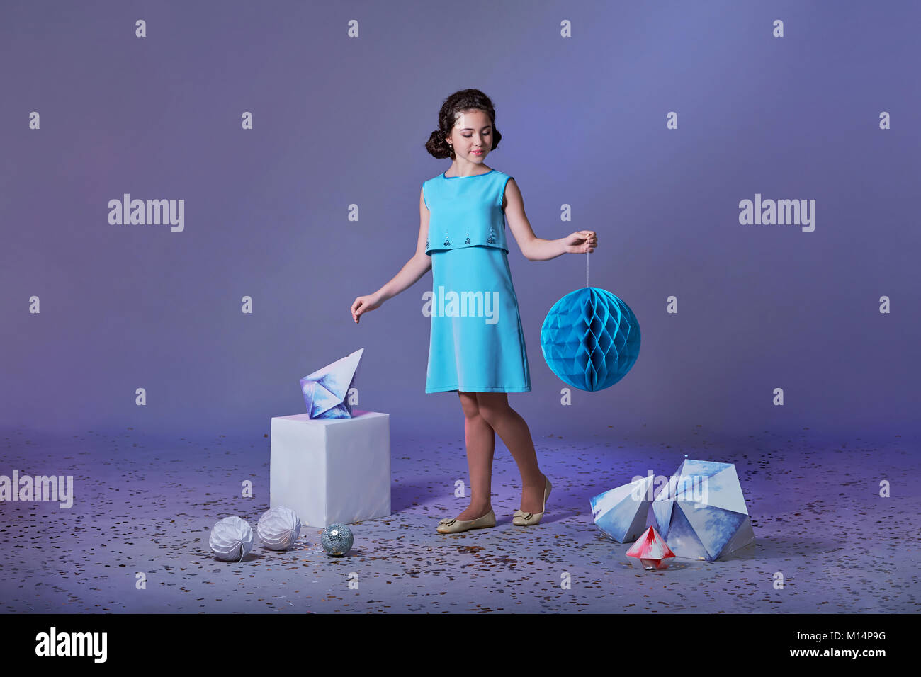 Hübsches Mädchen in einem eleganten blauen Kleid für Mädchen im Teenageralter mit einem Make-up. Origami und Minimalismus. Mode Kinder. Stockfoto