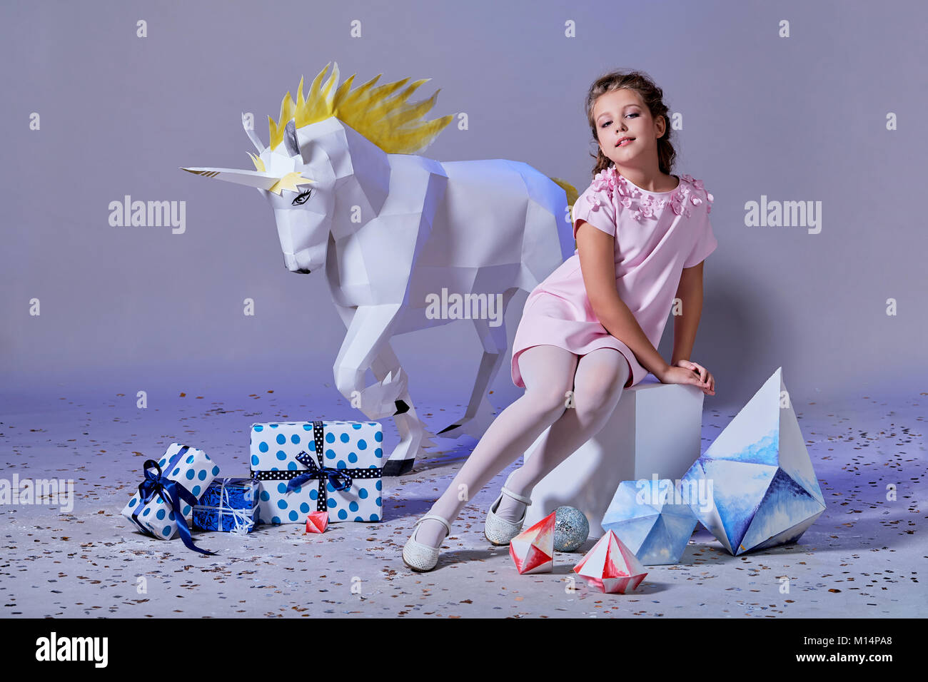 Fashion Kid. Designer Kollektion. Weiß groß Einhorn origami aus Papier. Mädchen in schönen rosa Kleid. Studio gedreht. Stockfoto