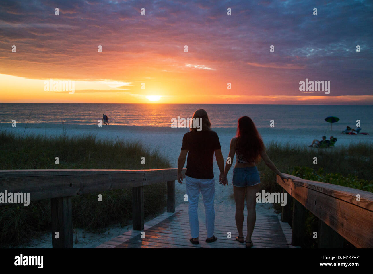 Schönes verliebtes Paar Silhouetten halten sich an den Händen und laufen auf dem exotischen Sandstrand romantischen Sonnenuntergang, Strand von Naples Pier, Florida, USA Stockfoto