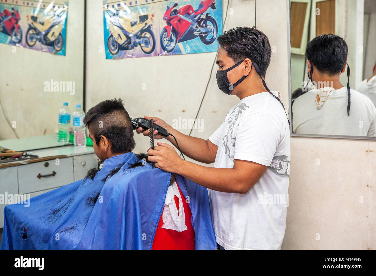 Ein Filipino Friseur schneidet eine hohe und enge fade Frisur auf ein Teenager in Barretto, Luzon, Philippinen. Stockfoto