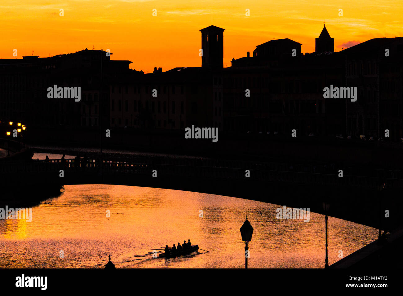 Silhouette von Pisa - Sonne auf der Stadt Pisa über den Fluss Arno in der Nacht, während eine rudernde Mannschaft Zeile unterhalb einer Brücke Stockfoto
