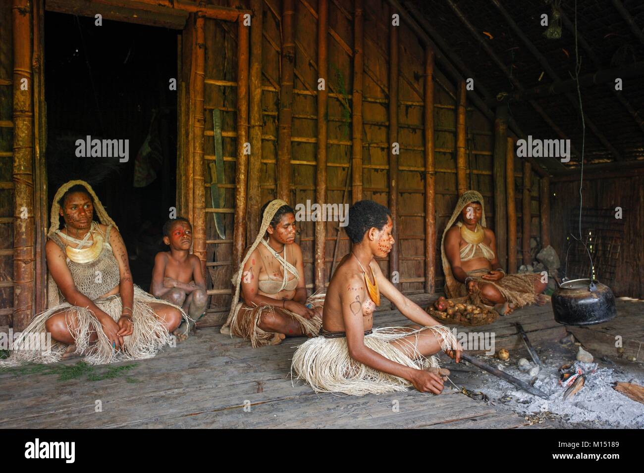 Papua-neuguinea, Southern Highlands, während des Wartens auf das Singen - Singen, die nicht statt, weil der Regen, die jungen Mädchen kochen, etwas Wasser und Kochen caocao (süsskartoffeln) unter der Asche, die Kleider sind ganz oben mit Bush Materialien Stockfoto