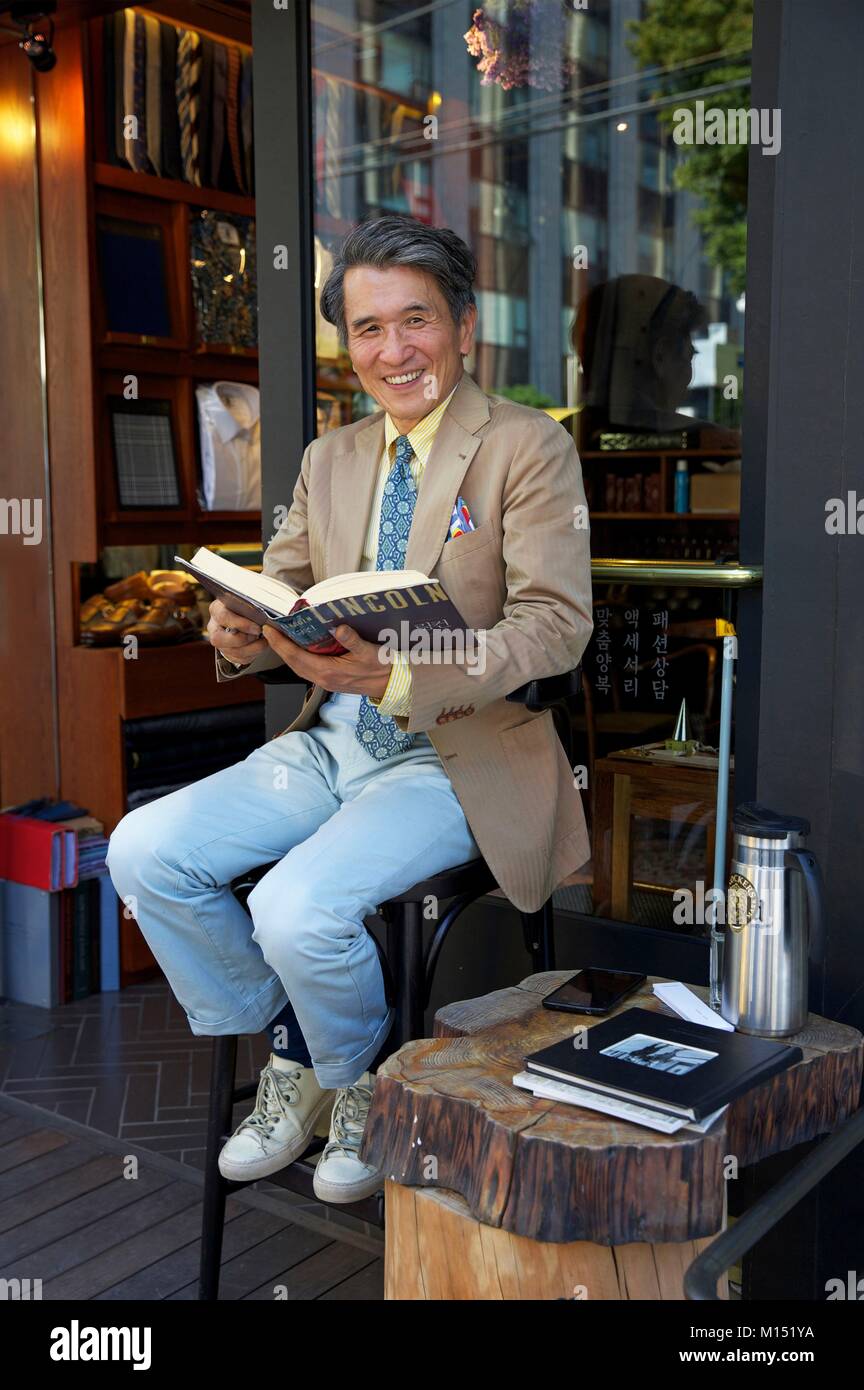 Südkorea, Seoul, Gyedong, eleganten Mann im Kostüm sitzend vor seinem Bücher Shop Stockfoto