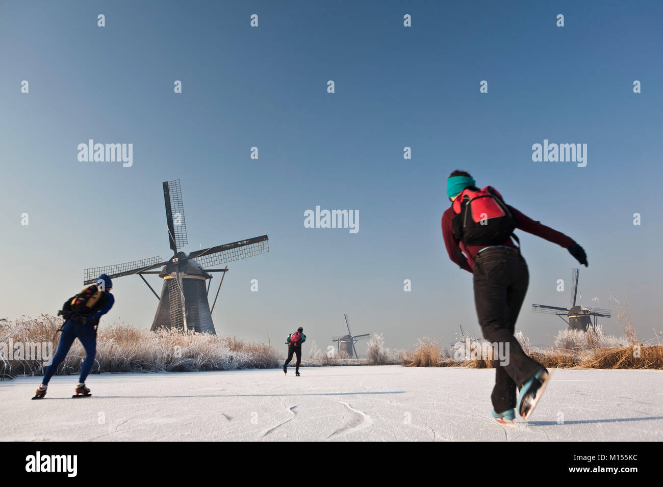 Die Niederlande, Kinderdijk, Windmühlen, UNESCO-Weltkulturerbe. Leute Eislaufen. Winter. Stockfoto