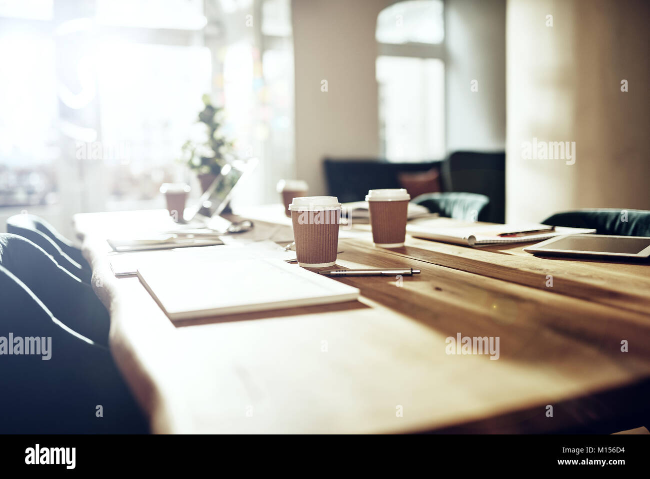 Innenraum eines leeren Tisch in einem Büro nach Stunden mit einem Laptop, takaway Kaffeetassen und Schreibarbeit abgedeckt Stockfoto