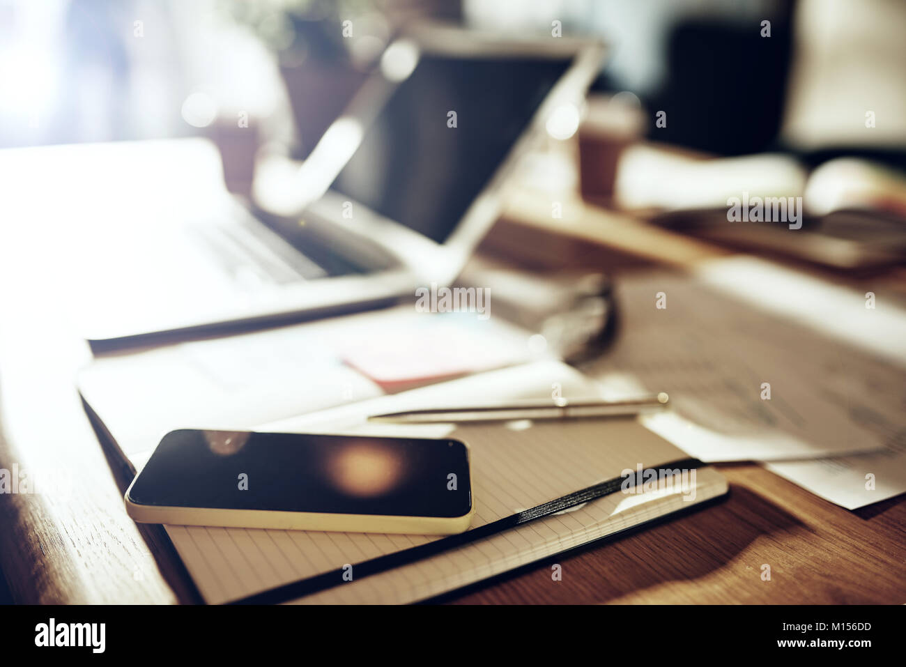 Nahaufnahme einer Tabelle in einem Büro nach Stunden mit einem Laptop, ein Handy und Schreibarbeit abgedeckt Stockfoto