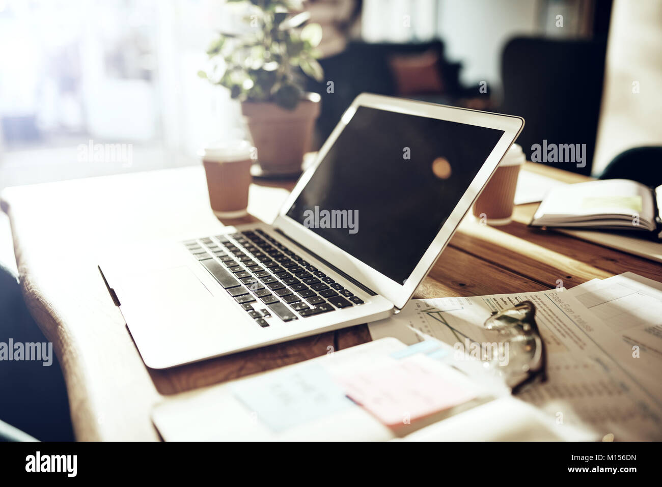 Tabelle in einem Büro nach Stunden mit einem Laptop und in Dokumenten und Unterlagen abgedeckt Stockfoto