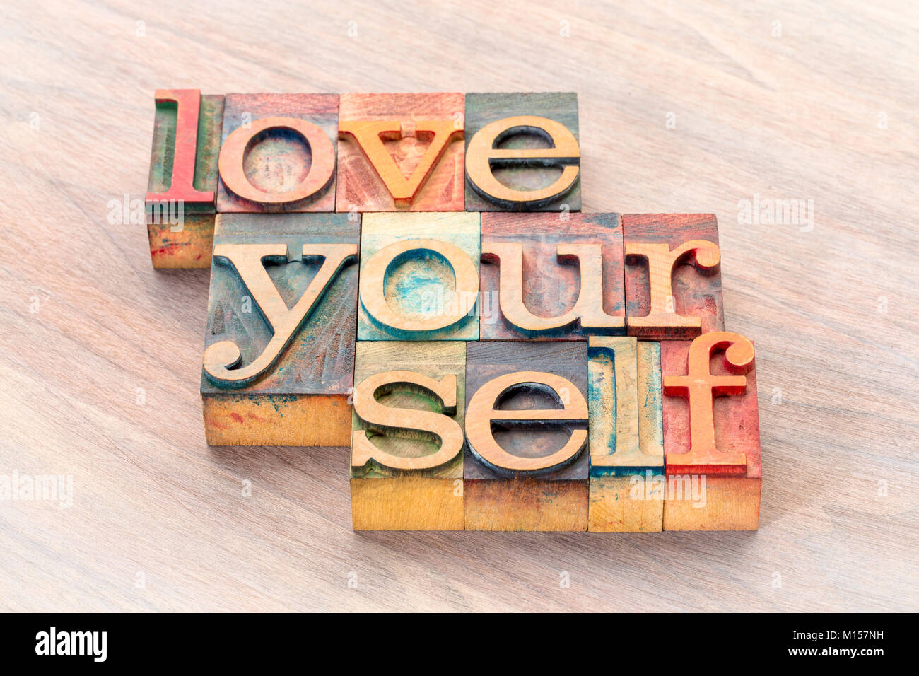 Liebe dich selbst word Abstract in letterprtess Holz Bausteine vom Typ befleckt durch Farbe Tinten Stockfoto
