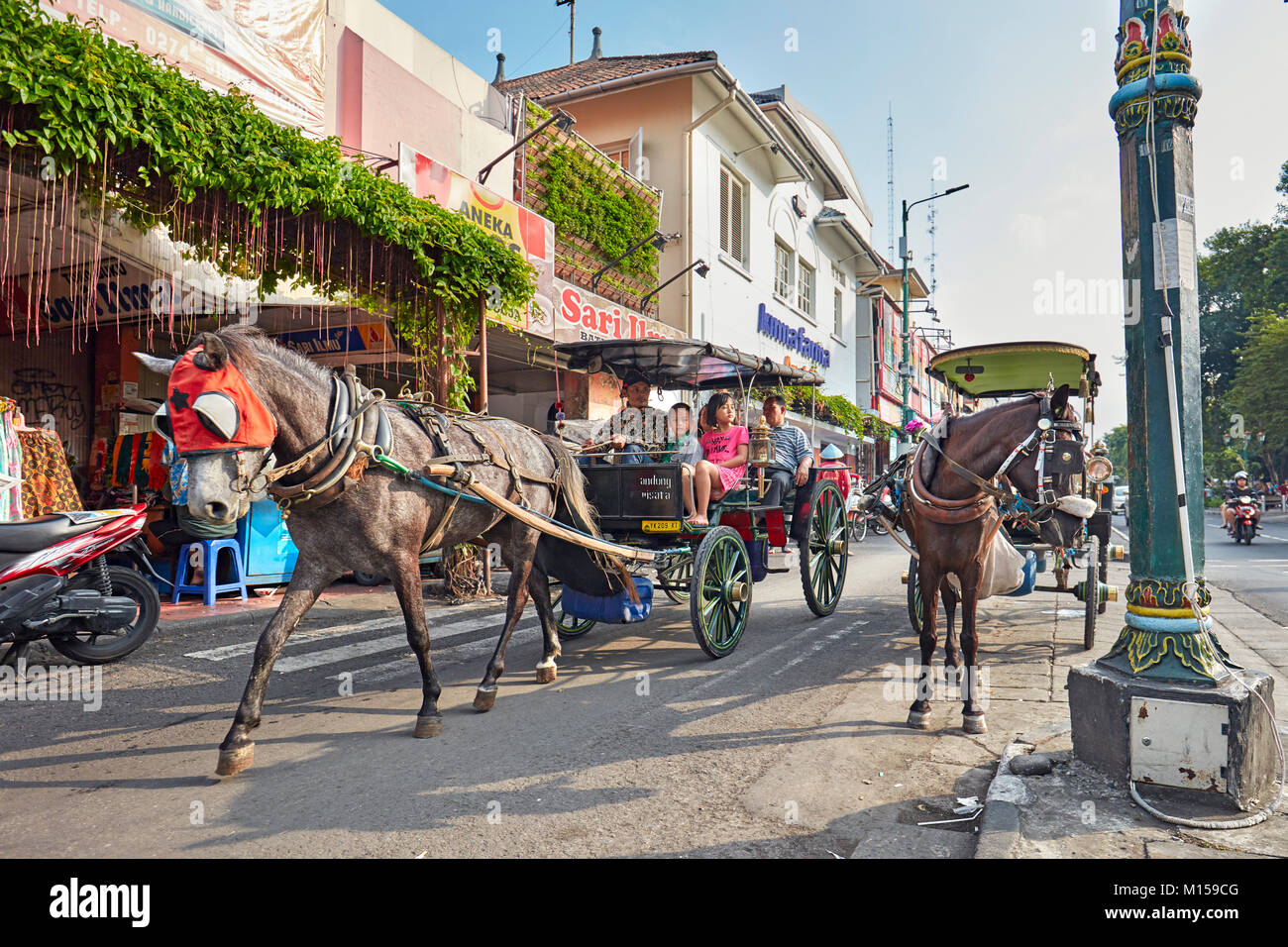 Pferdekutsche mit bewegenden Fahrgäste entlang Malioboro Street entfernt. Yogyakarta, Java, Indonesien. Stockfoto