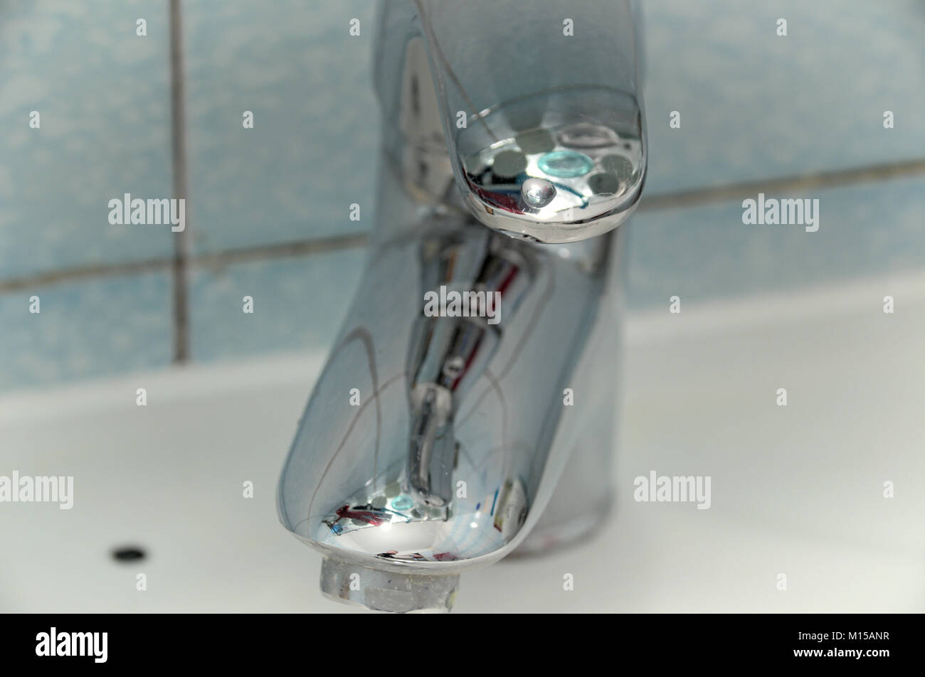 Glänzende Badewanne Armatur, reflektierende Mischen tippen, mit interessanten Überlegungen, auf ein Waschbecken mit Fliesen als Hintergrund montiert Stockfoto