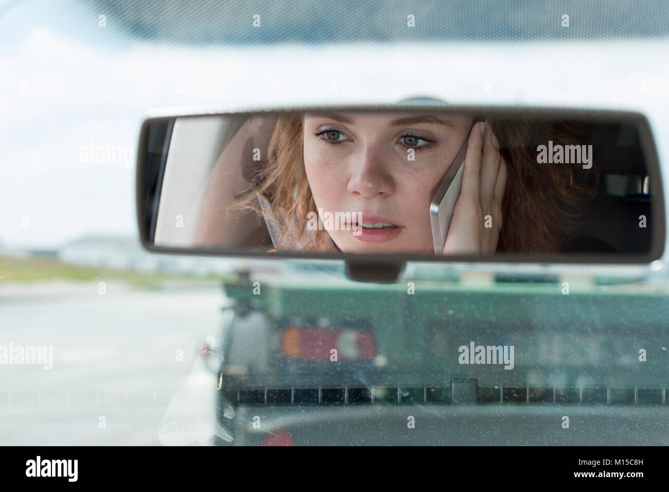 Eine junge Frau fährt ein Auto und Gespräche am Telefon und ist abgelenkt Stockfoto