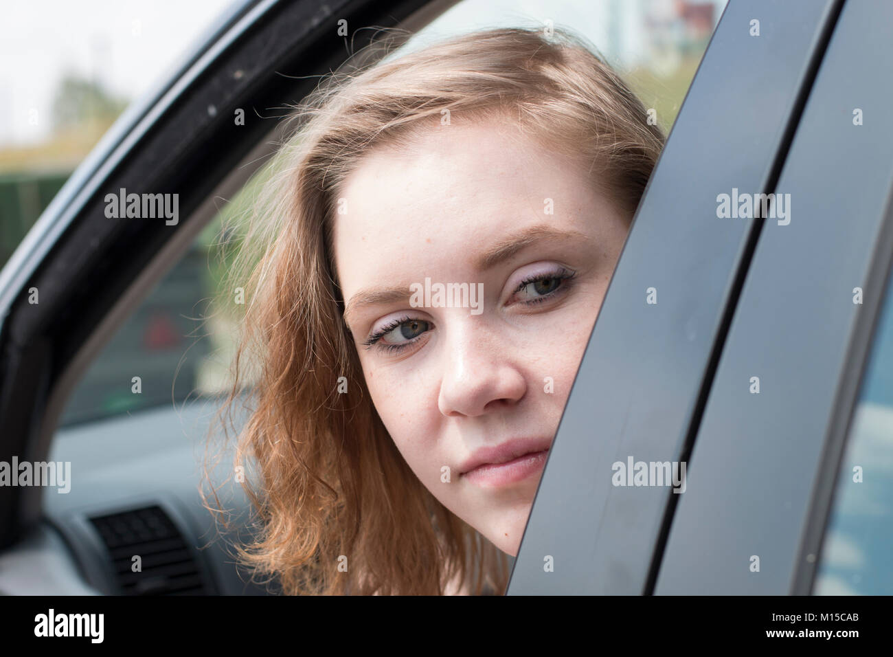Eine Frau in einem Auto ist Blick aus dem Fenster und sieht zurück, um den Verkehr zu prüfen. Stockfoto