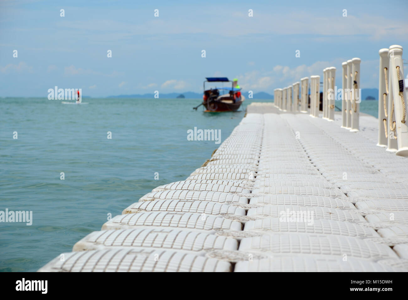 Pier gegen das Meer, das Boot und die Berge, Fokus auf den Vordergrund Stockfoto