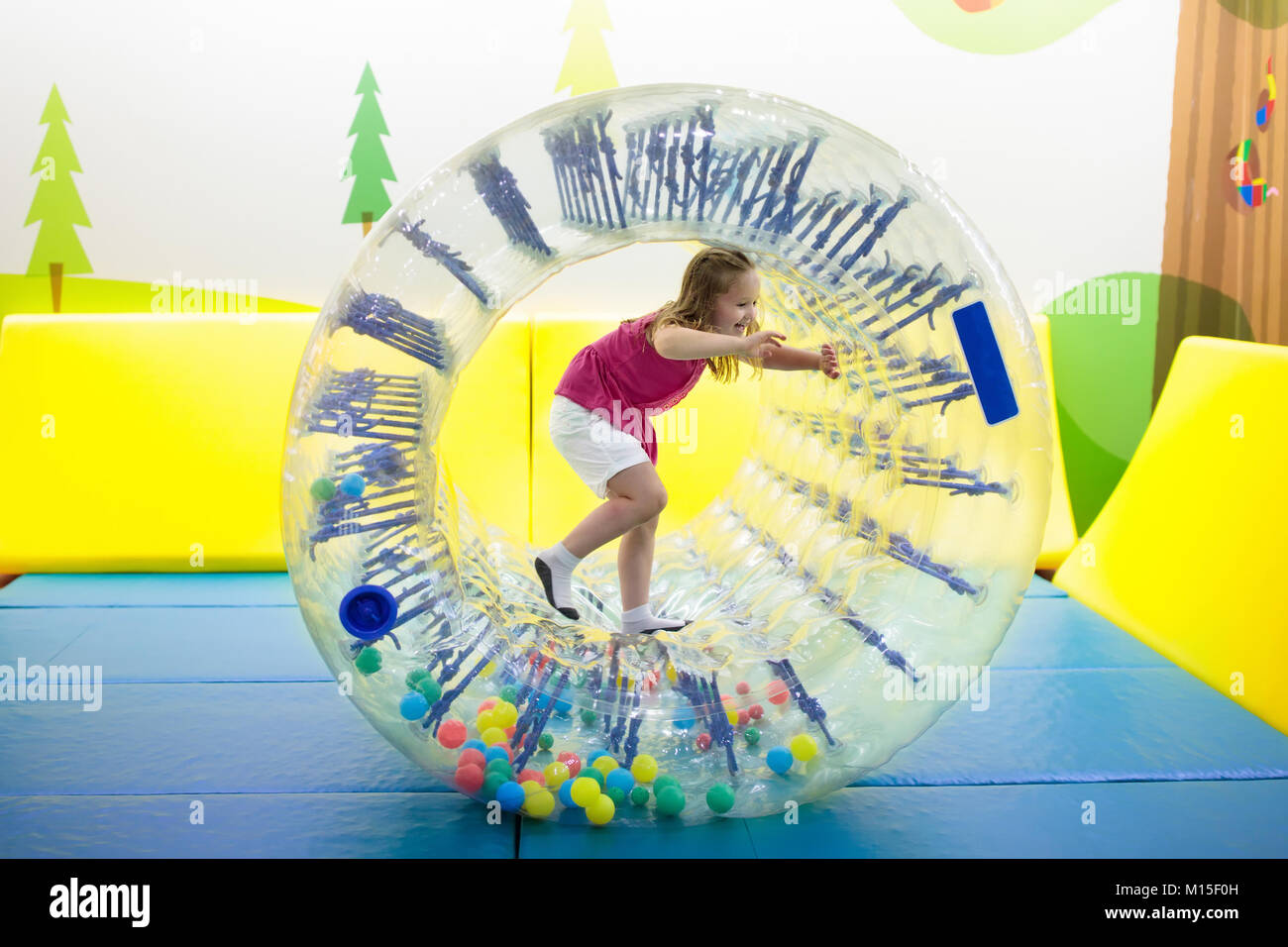 Kind im Laufrad springen auf bunten Spielplatz Trampolin. Kinder springen in Aufblasbare bounce Burg auf Kindergarten Geburtstag. Aktivität und pl Stockfoto