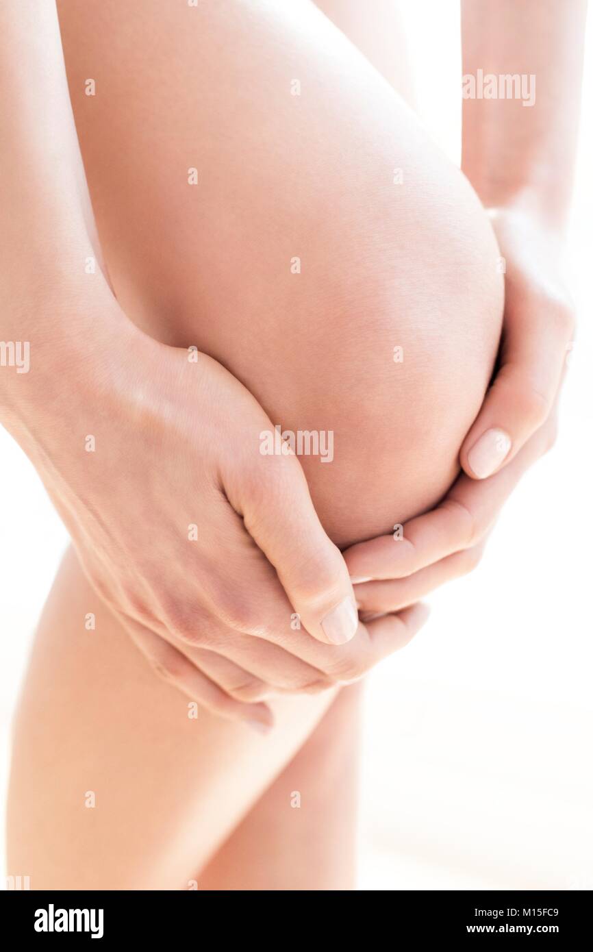 MODEL RELEASED. Junge Frau in Schmerzen ihrer wunden Knie reiben, bis zu schließen. Stockfoto