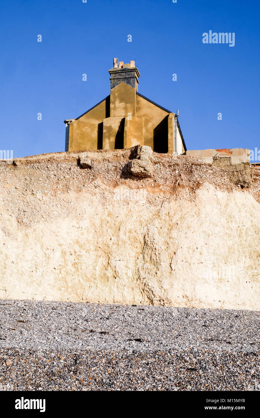 Erosion der Seite eines terreced Haus saß am Rande eines großen weißen Kreidefelsen Gesicht, das mit einem Kiesstrand an der Unterseite der cli abgefressen hat Stockfoto