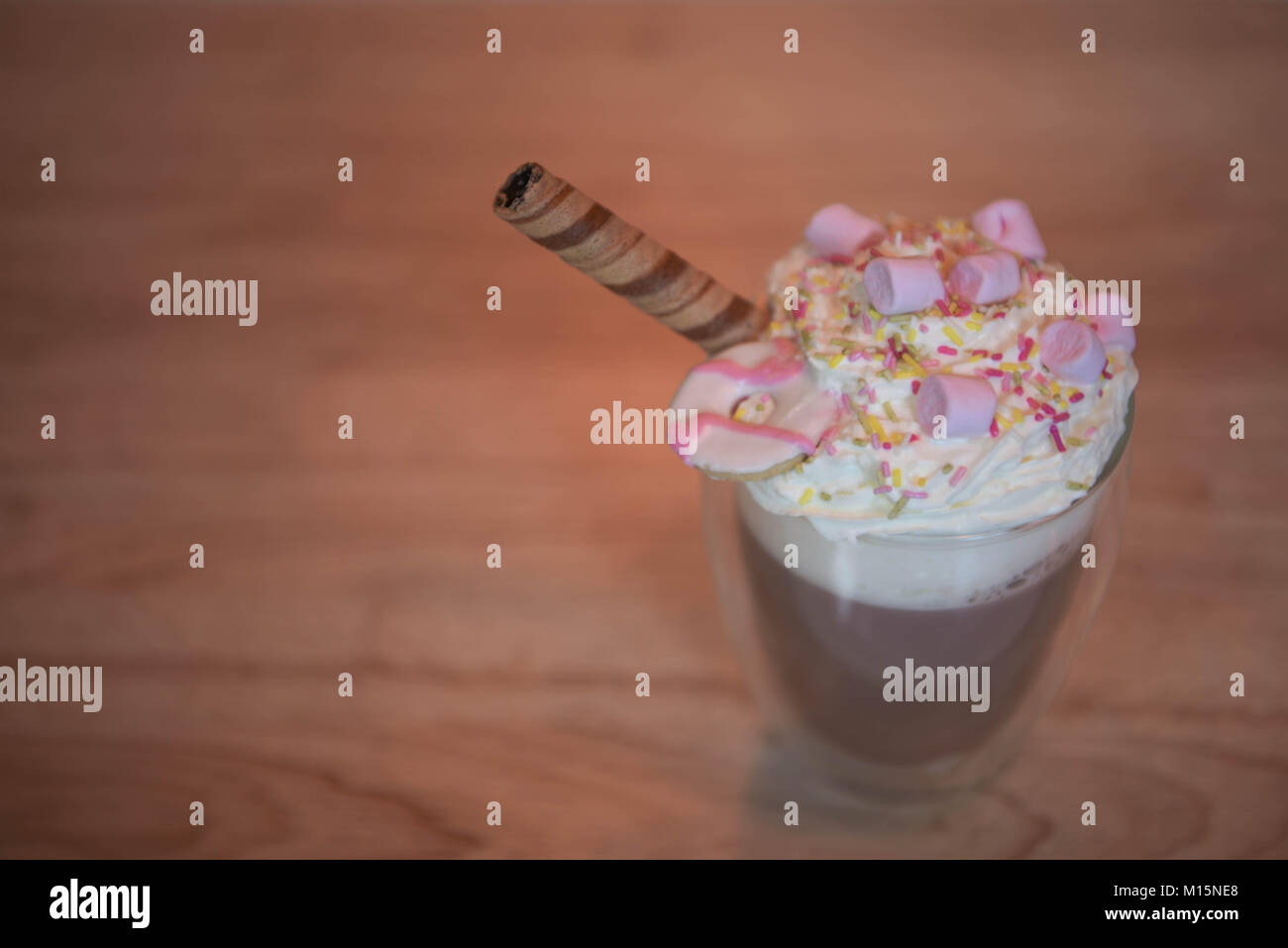 Köstliche heiße Schokolade trinken Drink mit Ansicht des Schlagsahne topping besprüht und rosa Marshmallows auf Holz Tisch Hintergrund Stockfoto
