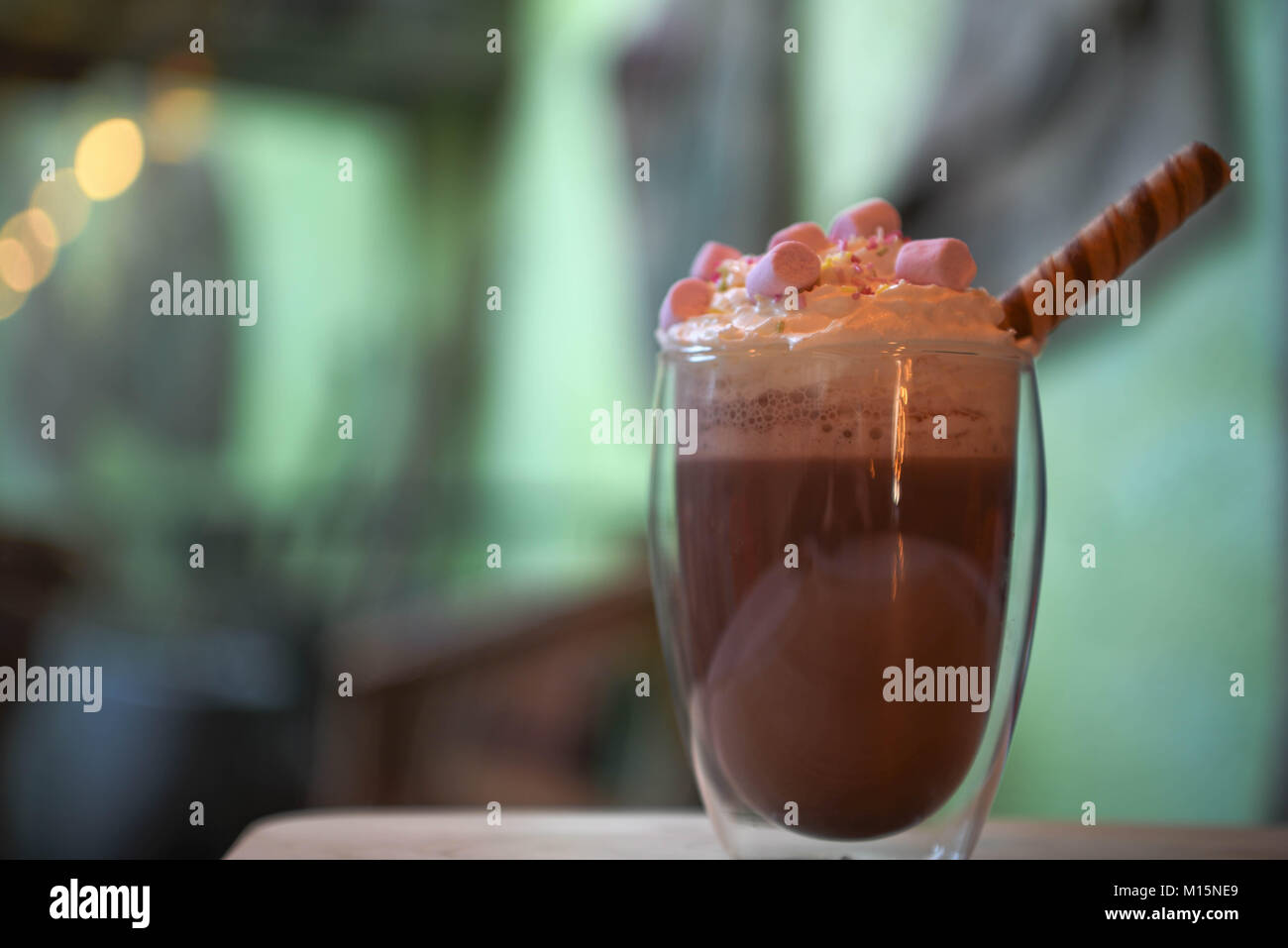 Köstliche heiße Schokolade trinken in ein Glas mit Schlagsahne rosa Marshmallows mit Schokolade Stick und Unschärfe zimmer Hintergrund im Licht überstieg Grün Stockfoto