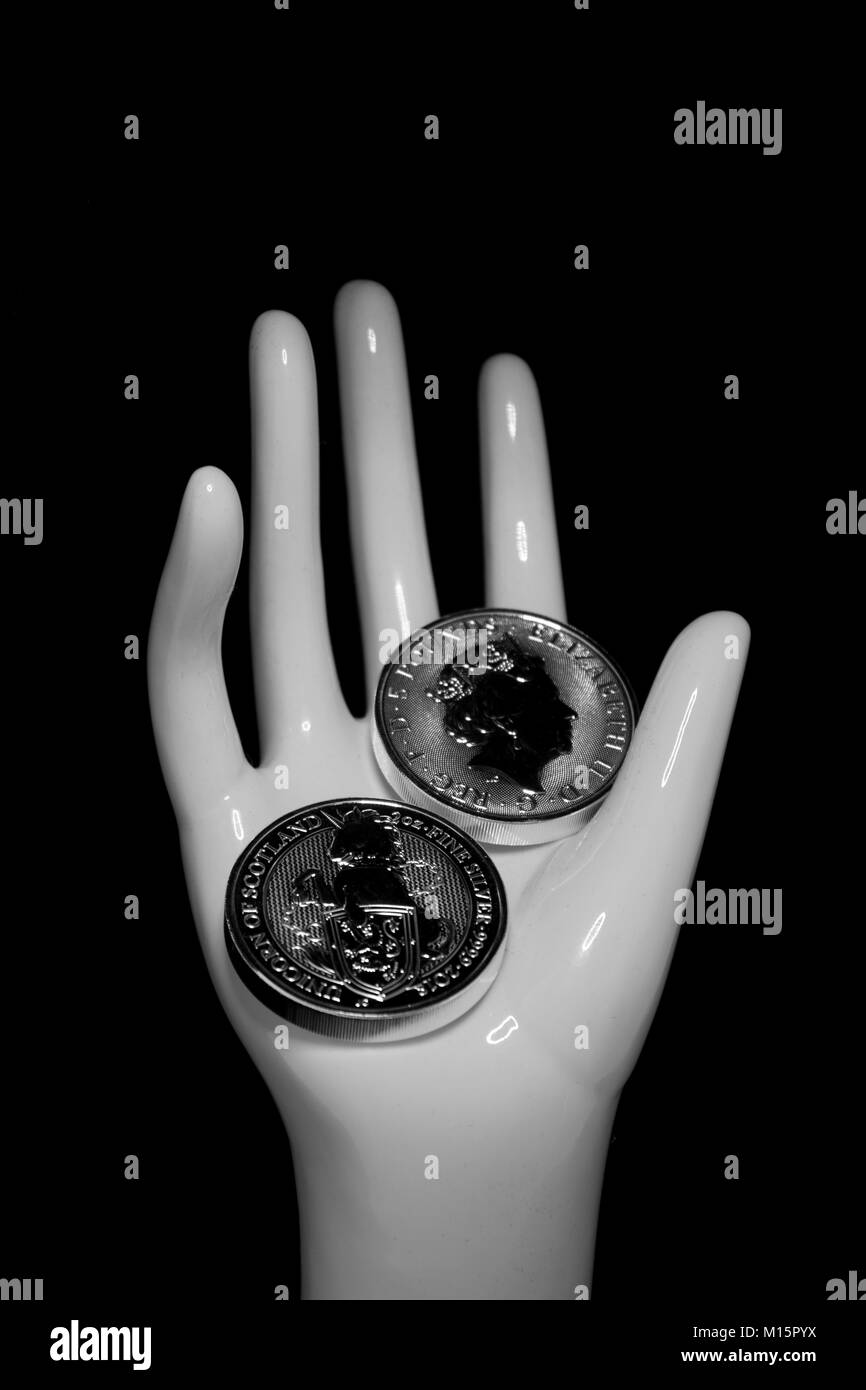 Auf einem schwarzen Hintergrund ist eine Hand, die mit der Investition in Silber Münzen eines crypto Währungen. Einhorn von Schottland. Stockfoto