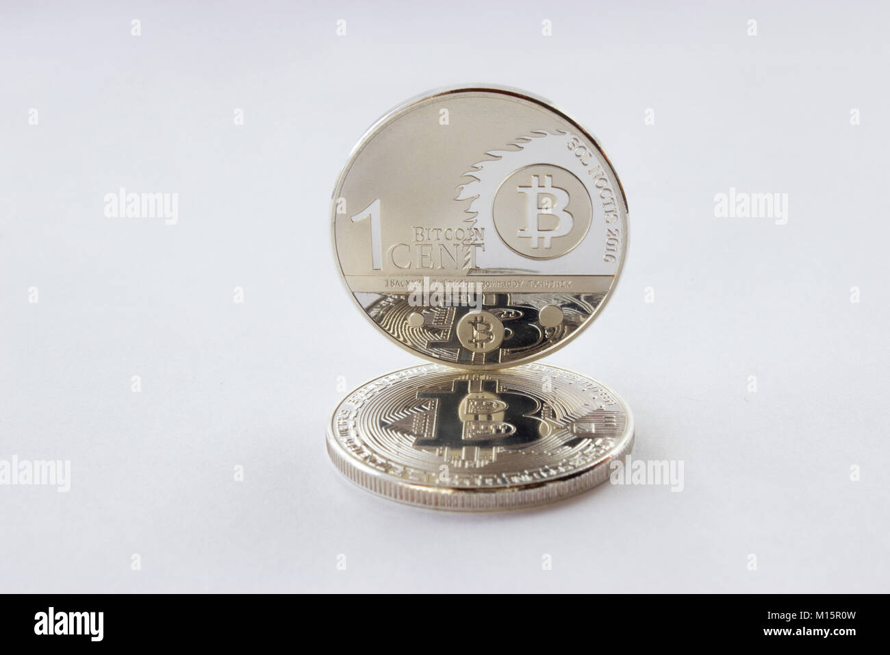 Auf einem weißen Hintergrund sind Silber Münzen eines digitalen crypto Währungen - einen Cent und bitcoin. Cent von den bitcoin steht auf einem liegenden Bitcoin. Stockfoto