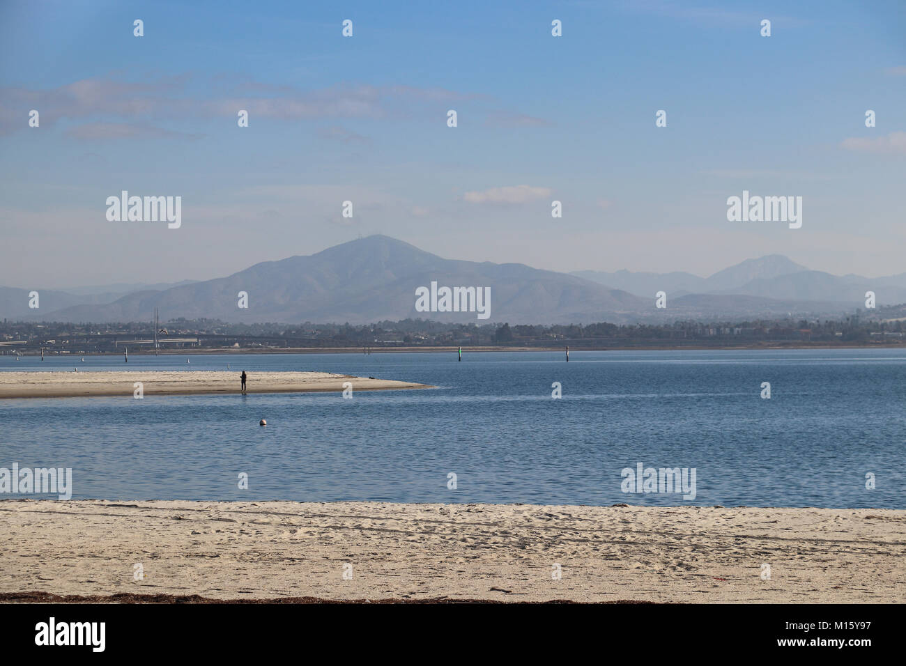 Einsame silhouette Abbildung Angeln aus einem weißen Sandstrand mit blauen Bucht von San Diego und Mt. Miguel im Hintergrund, weißer Sand im Vordergrund, kopieren. Stockfoto