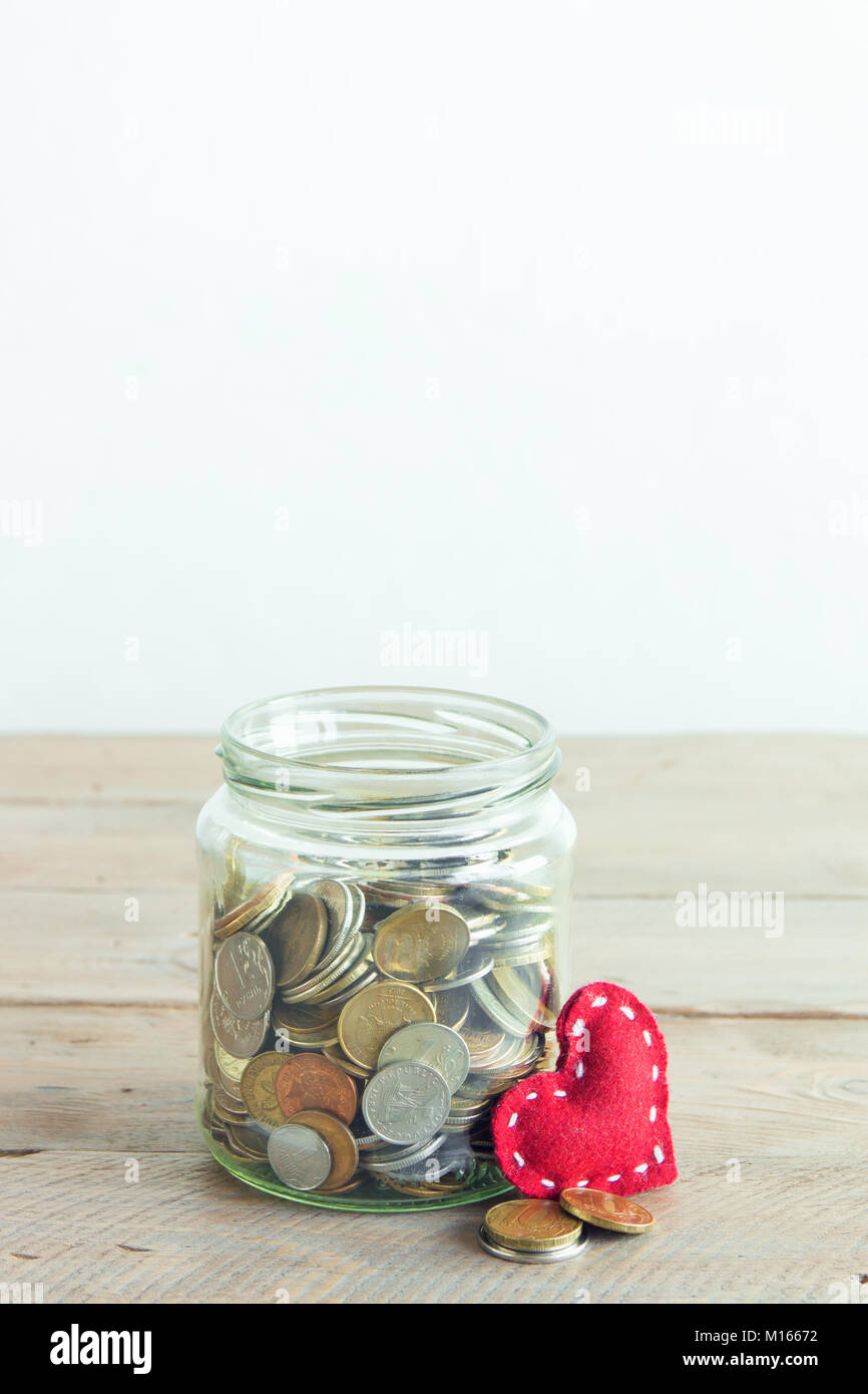 Münzen in Glas Glas mit roten Herzen. Kosteneinsparungen, Nächstenliebe und Spendenkonzept, kopieren. Stockfoto