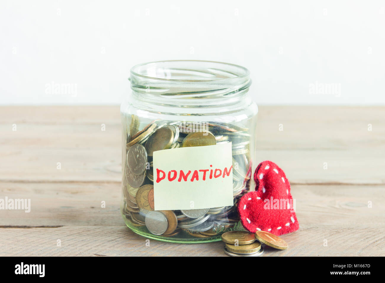Münzen in Glas Glas mit roten Herzen und Spende label. Kosteneinsparungen, Nächstenliebe und Spendenkonzept, kopieren. Stockfoto