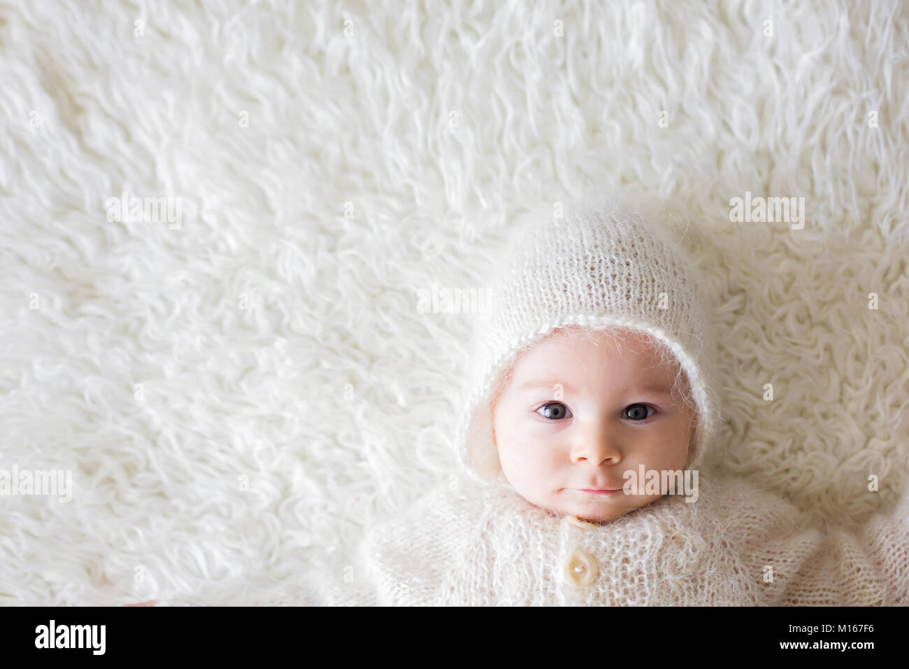 Schließen Portrait eines kleinen Baby boy in Weiß gestrickte Body und ein Hut, lächelnd Stockfoto