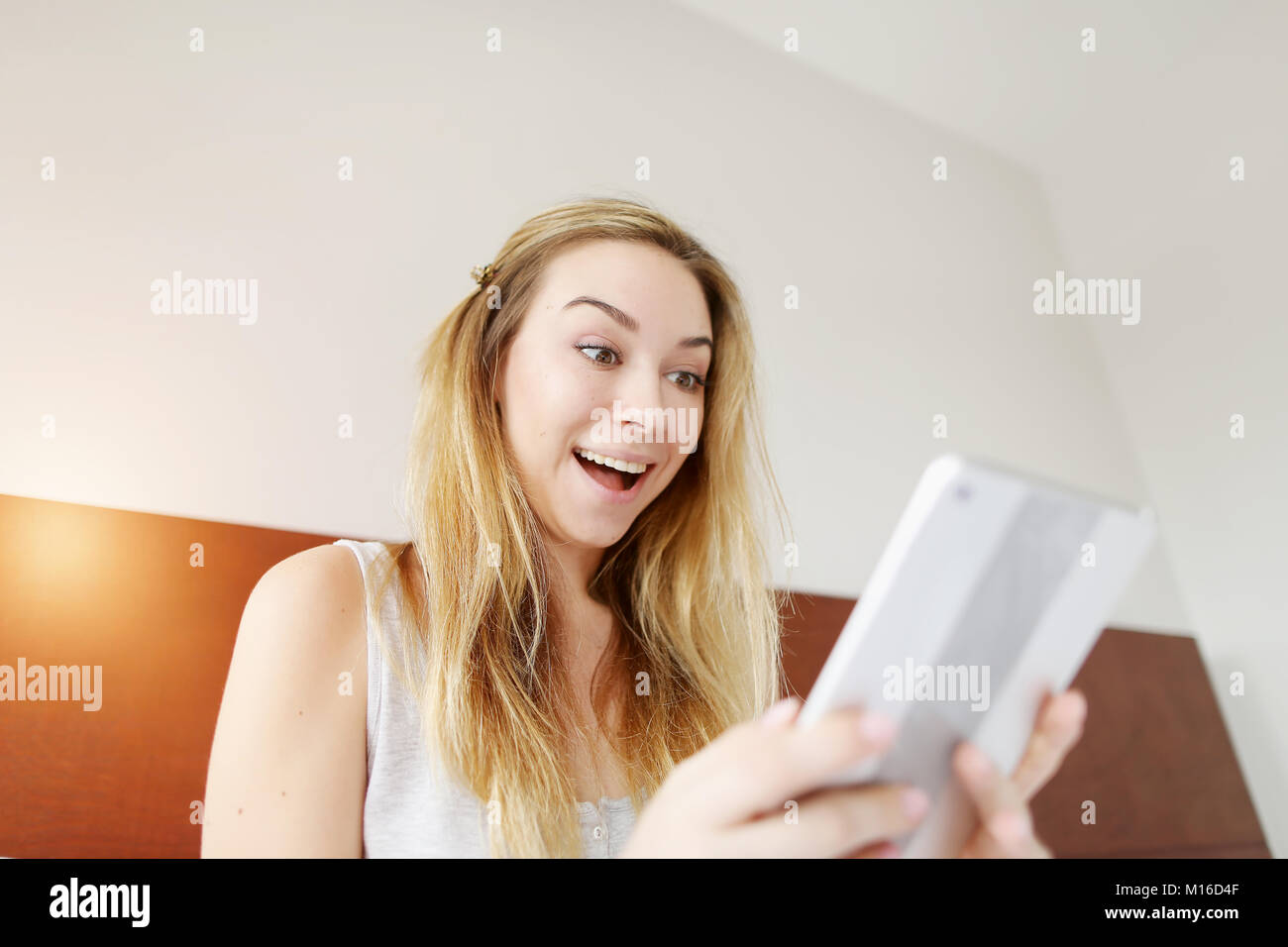 Crazy glückliche junge Frau smilling mit Tablet am weißen Bett Stockfoto