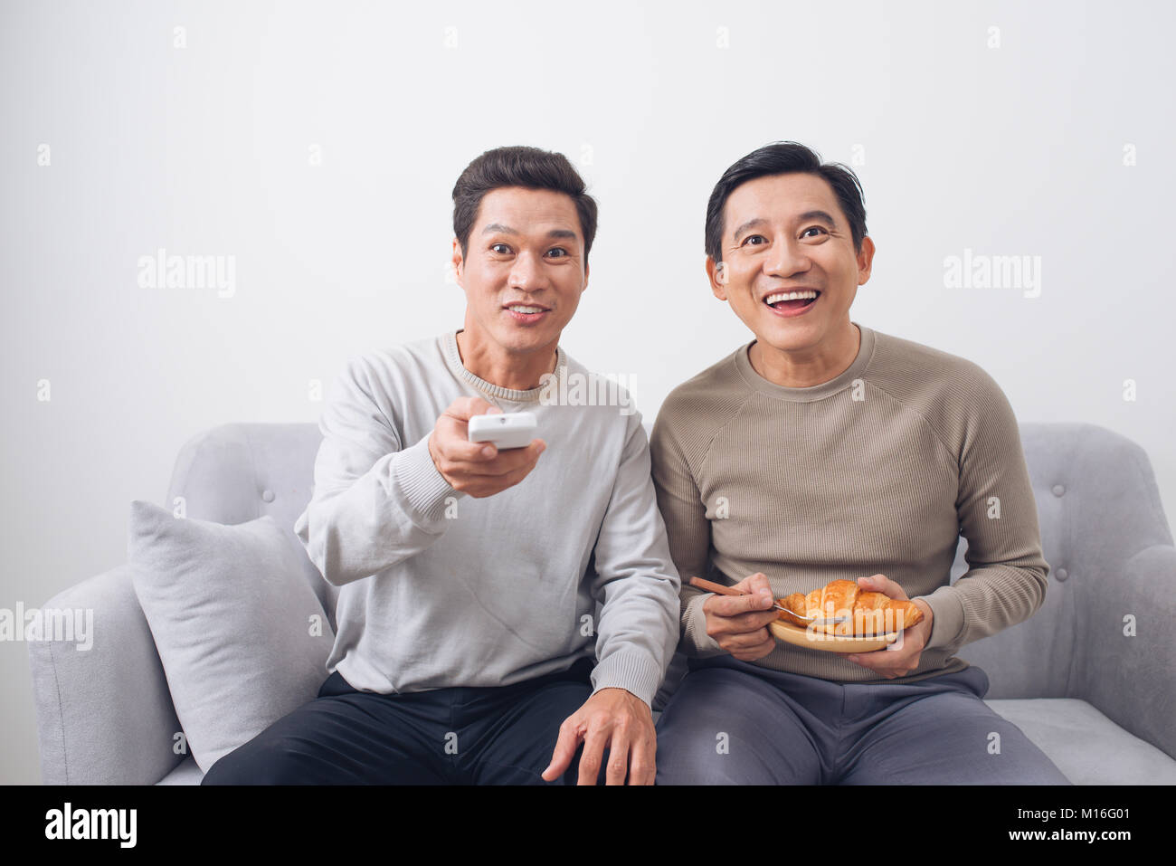Zwei männliche Freunde, Fußball sitzen auf einem Sofa zu Hause Stockfoto