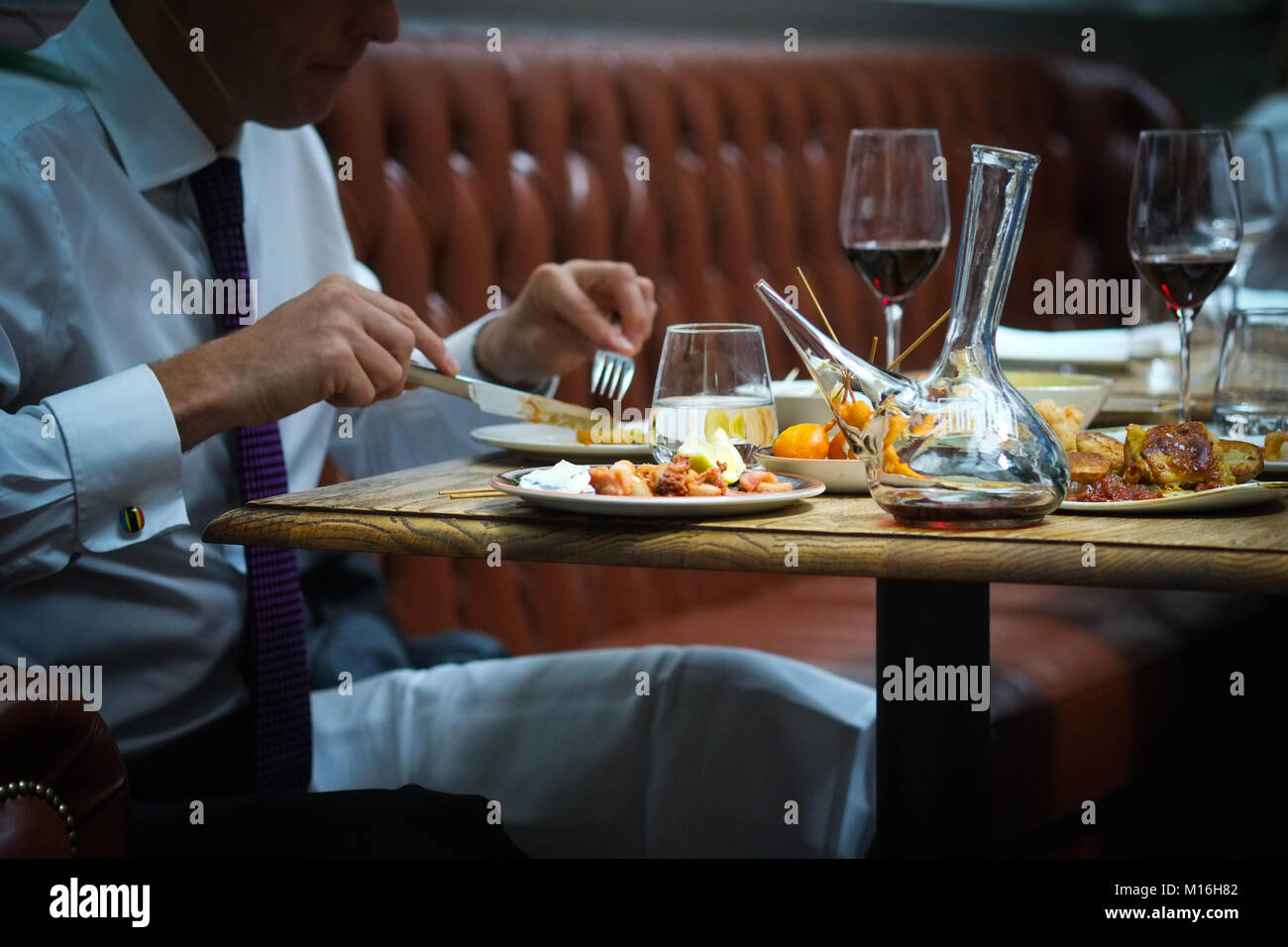 Business Lunch von Tapas im Iberica Restaurant. Mann in Anzug, Tapas essen mit einem porron Rotwein. Stockfoto