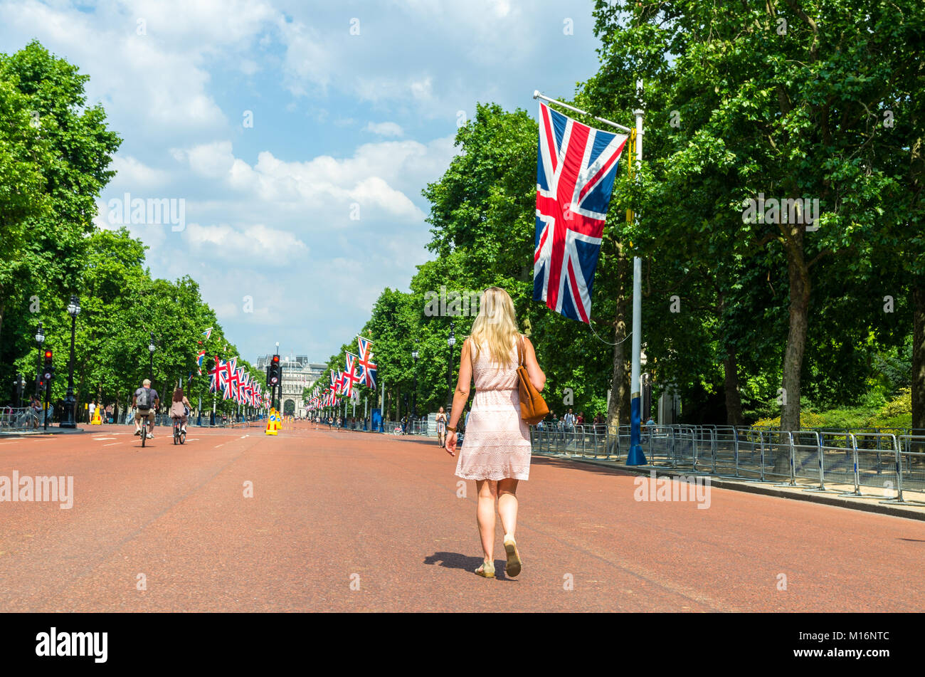 Eine Frau geht durch die Mall in Richtung der Admiralty Arch als Union Jack Fahnen der berühmten Avenue in Westminster, London Line Stockfoto