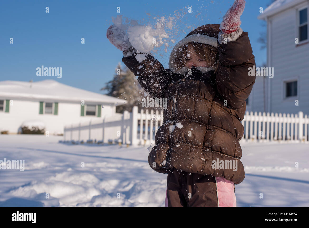 Ein 3-jähriges Kind wirft Schnee in der Luft im Winter Tag in den Vereinigten Staaten. Stockfoto